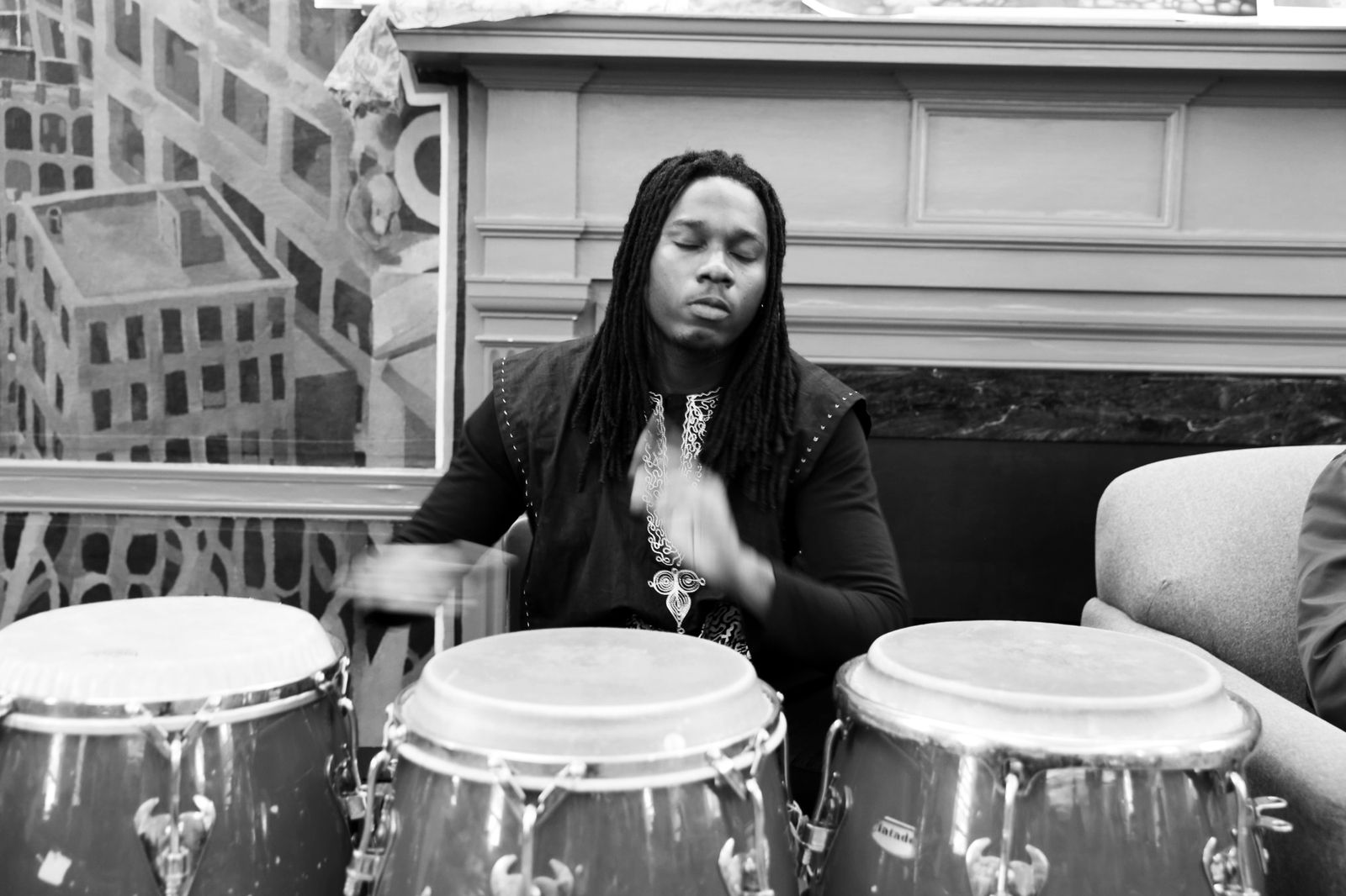 Roth$child at a row of three congas, eyes closed, hands blurred mid-stroke.
