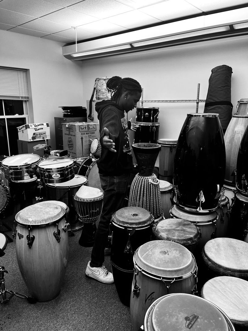 Roth$child with arms open in a room packed with congas, djembes and drum kits.