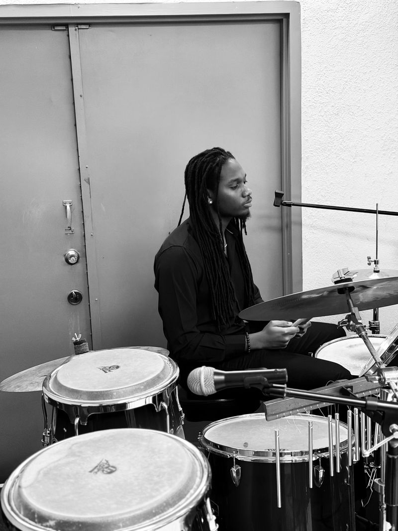 Roth$child seated behind a drum kit with congas and chimes in the foreground.