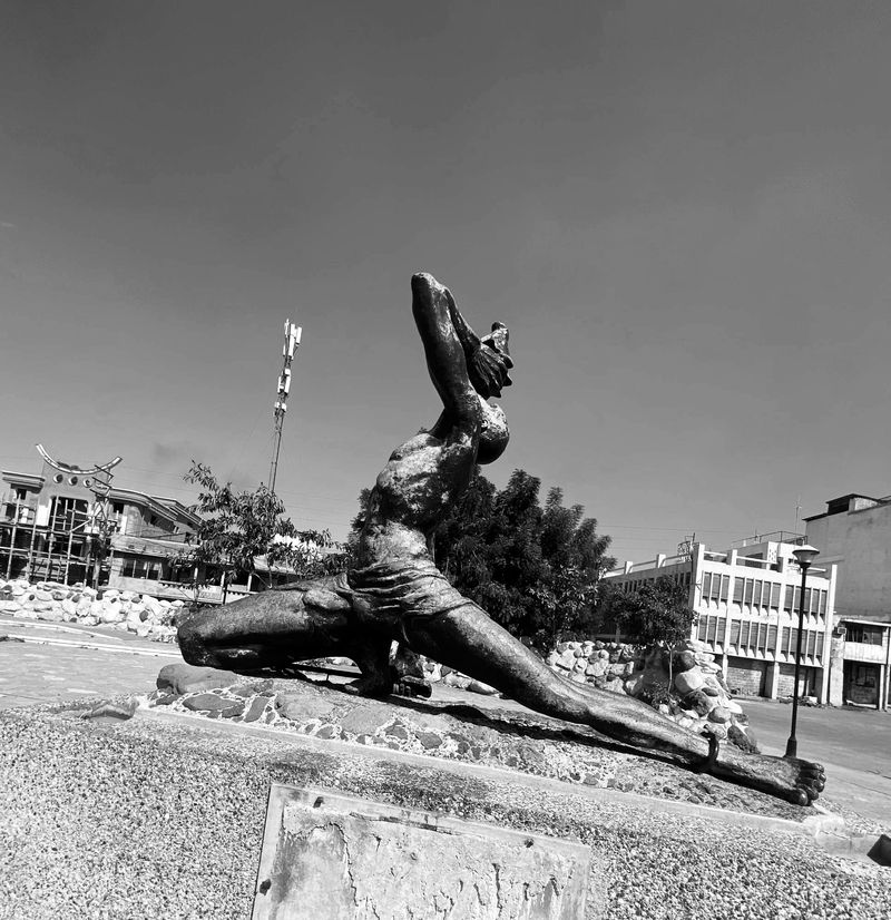 The Nèg Mawon statue in Port-au-Prince: a kneeling figure blowing a conch shell, one leg stretched out with a broken shackle at the ankle.